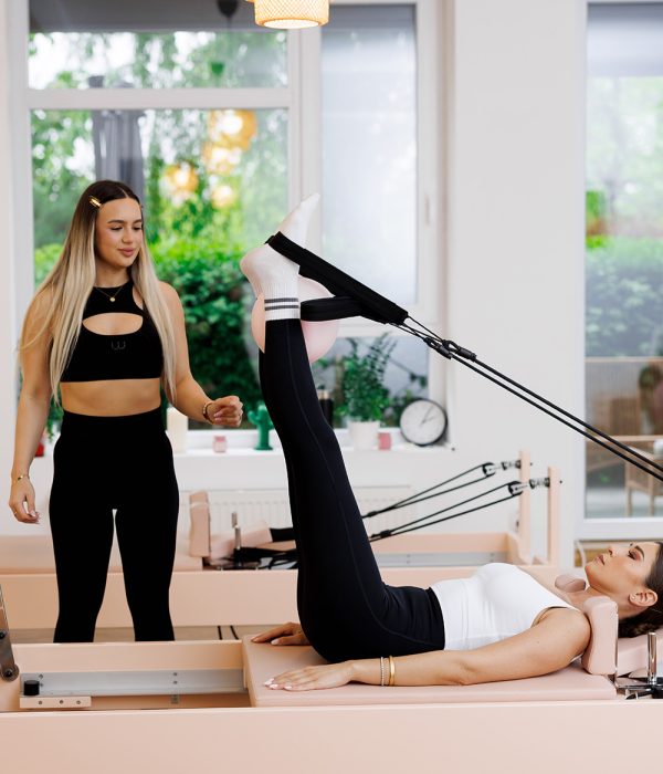 Instructor personal trainer supraveghind exercițiu pe aparat pilates reformer la studioul Yaara Wellness București